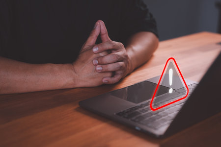 Male user use a laptop with caution warning sign for notification error. Concept cyber security technology of computer virus detect, personal data protection, network security and maintenance.の写真素材