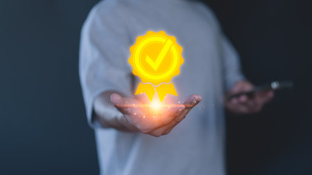 Person holds a glowing digital certification badge with a check mark symbol, symbolizing approval, quality assurance, achievement, excellence, and certification in a professional or business context.の写真素材