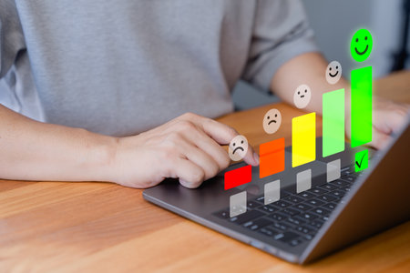 Customer using a laptop select a happy face icon from a feedback scale with five emoji option, symbolizing customer satisfaction, review, and positive user experience in an online feedback system.の写真素材