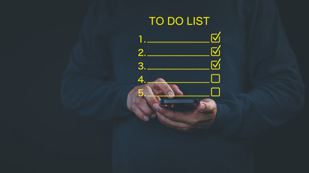 Person holding a smartphone with a virtual screen "To-Do List" overlay, featuring checked and unchecked tasks. Represents productivity, task management, digital checklist option, and planning work.の写真素材