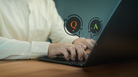 Person types on a laptop computer with virtual Q&A speech bubbles, representing online communication, chatbot AI systems, or customer support interaction.の写真素材