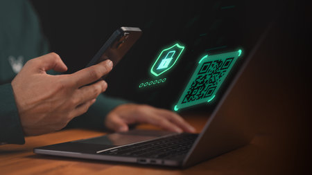 Man using smartphone and laptop with digital QR code and security icon, representing online payment,...
