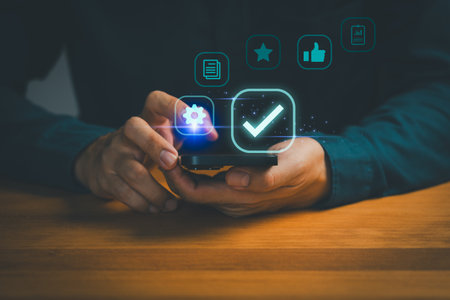 Person holding smartphone with digital icons of settings, checkmark, star, like, and documents, symbolizing mobile app approval, user satisfaction, quality assurance and digital technology management.の写真素材