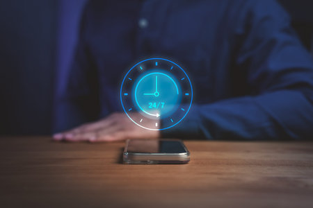 A glowing digital clock icon showing 24/7 above a smartphone on a wooden table, symbolizing nonstop...