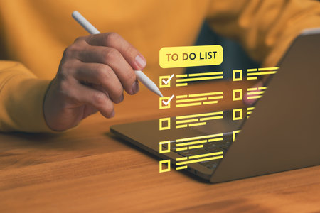 Man using laptop computer with To Do List checklist interface, symbolizing productivity, task...
