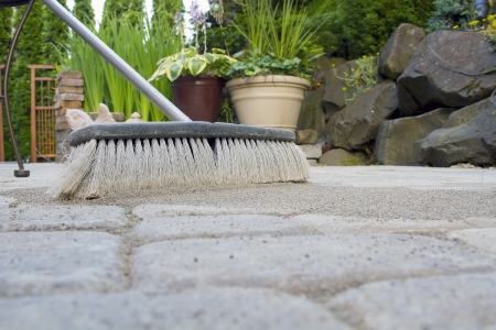 Broom Sweeping Locking Sand Into Backyard Patio Pavers Low Viewの写真素材