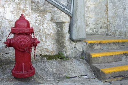 Red Fire Hydrant by the Staircase with Grunge Textured Wall Backgroundの写真素材