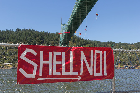 PORTLAND, OREGON - JULY 29, 2015: Greenpeace USA activists rappelled off St Johns Bridge over Willamette River in Portland Oregon in protest and preventing the Shell Oil Icebreaker Vessel from leaving for oil drilling in the Arctic with red banner sign onのeditorial素材