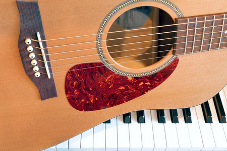 Acoustic Guitar sitting on Piano Keyboard Closeupの写真素材
