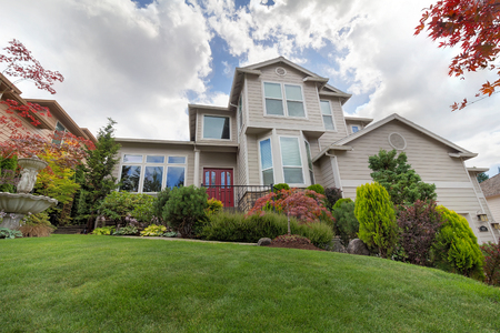 Front lawn of traditional house with manicured landscaping water fountain green grass plants trees shrubsの写真素材