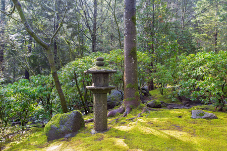 Stone Pagoda Lantern Sculpture at Japanese Garden with trees shrubs rocks moss landscapingの写真素材