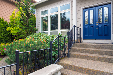 House with blue double doors concrete steps entry by landscaped front yard gardenの写真素材