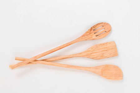 Three beautiful wooden kitchen ladles on a white background. Top view
