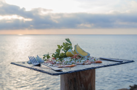 Picture landscape of a luxurious dish - Smoked salmon, fresh lemon and celery served on a black...