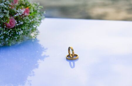 Top view of precious gold rings on a white table - Wedding rings with a bouquet of flowers - Close-upの写真素材