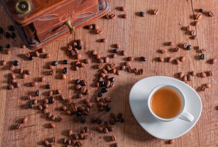 Top view of a white porcelain cup, roasted coffee beans and a red mill on a wooden table. Relaxation concept and coffee aroma.の写真素材