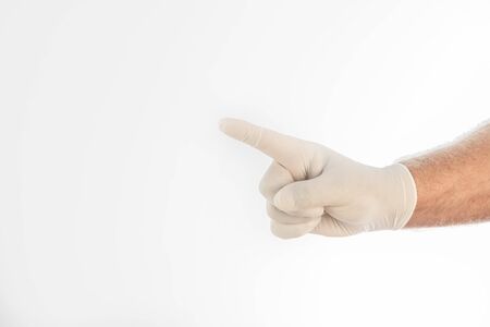 Man's hand covered by a medical glove, gesturing with his finger on a white background. Space for writing. Close-upの写真素材
