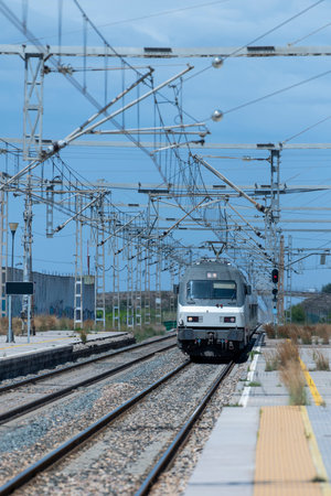 Railway station with fences, green trees and blue sky in the background. Vertical image