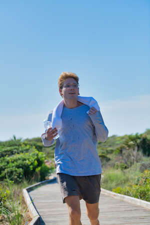 Photo portrait of a young man running in the morning with the blue sky in the background. Concept of healthy life with exercises. Vertical imageの写真素材