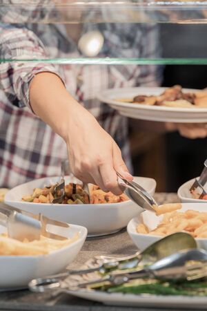 Girl whose face is not seen choosing food which has in front placed in a showcase concept of healthy food. Vertical image.の写真素材