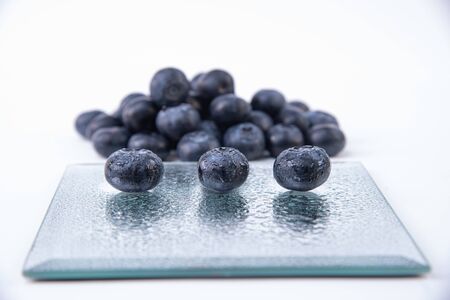 Ripe blueberries - Three big wet and ripe blueberries on a glass plate - Delicious bunch of blueberries - Blueberries close-upの写真素材