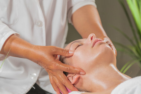 Close-up of young woman having chinese curative facial massage.relaxation and acupressure conceptの写真素材