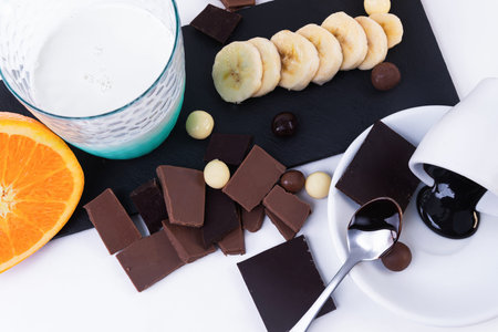 dark chocolate bars, chocolate chips banana an a glass of milk