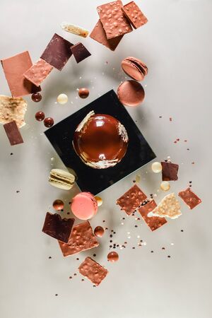 Big ball of dark chocolate surrounded by delicious macaron, chocolate balls and traditional chocolate sweetsの写真素材