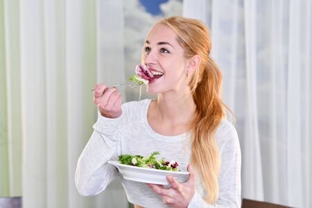 Woman smiles while eating a healthy saladの写真素材