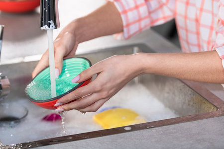 Woman rinsing a bowl under a faucet