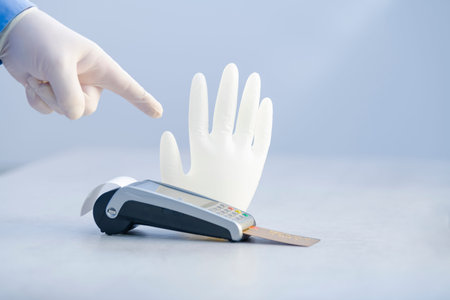 Close-up of a male hand using a glove pointing at a credit card reader in front of an inflated glove...