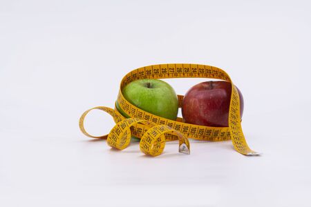 Green apple and red apple with measuring tape on white backgroundの写真素材
