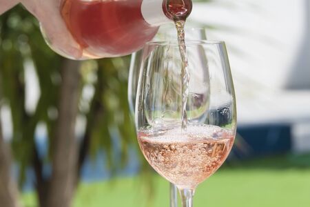 a hand of woman pouring delicious rose wineの写真素材