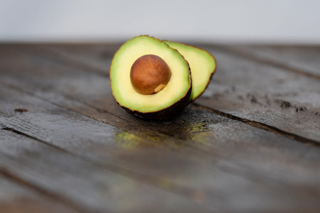 Close up of a freshly cut avocado with its seed on a wooden board on an out of focus background....