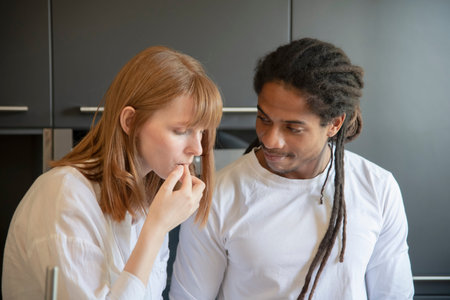 Focused beautiful woman touching her lips while a handsome black man looks at her lovingly on an out...