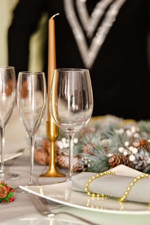 select focus of several glasses surrounded by beautiful Christmas decorations and a plate on an out of focus background. Christmas decoration concept.の写真素材