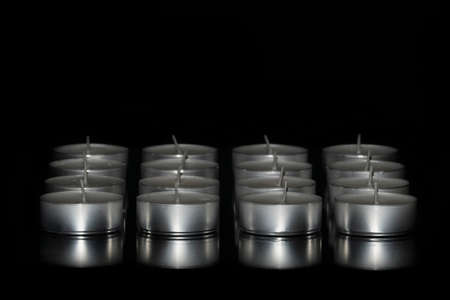 Selective focus of an arrangement of tea light candles on a dark background. Abstract concept.の写真素材