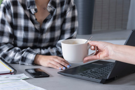 a young woman working from home and her mother gives a cup of coffee.