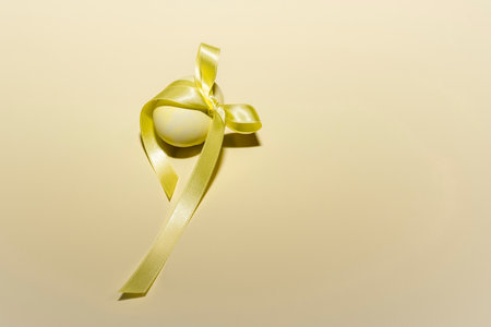 Close up of a yellow painted egg with a ribbonの写真素材