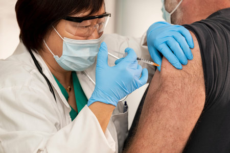 Female doctor carefully administering a vaccine to a male patientの写真素材