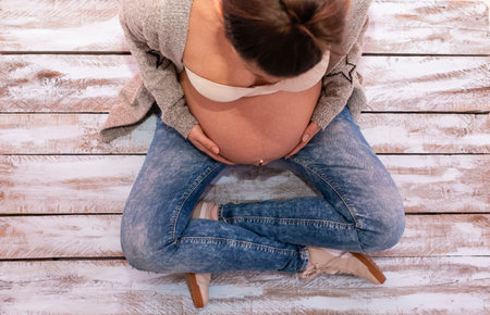 a pregnant woman sitting on a wooden floorの写真素材