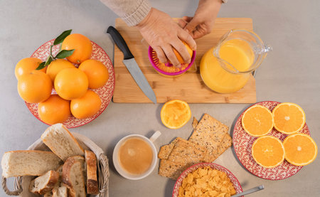 Woman preparing fresh orange juice in kitchen for breakfastの写真素材