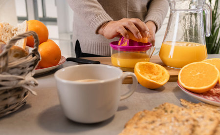 Woman preparing fresh orange juice in kitchen for breakfast
