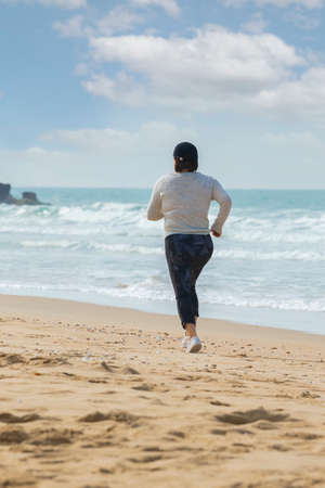 A mature woman running near the seashoreの写真素材