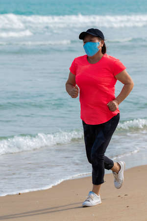 Asian woman with a mask running on the beachの写真素材