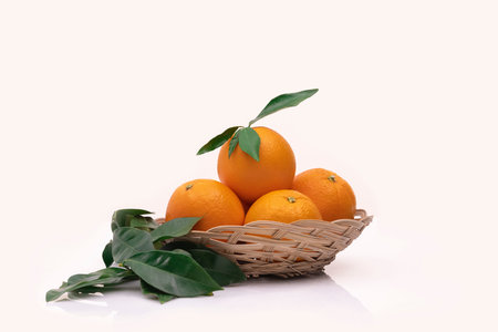 View of oranges in a basket with leavesの写真素材