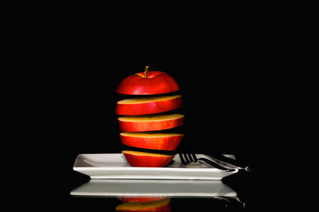 Seemingly floating red apple slices on a plateの写真素材