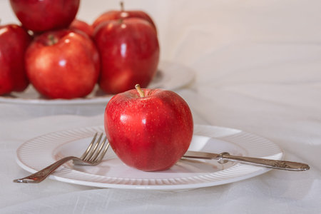 Juicy red apple with fork and knife on a plate