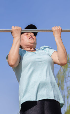 Asian woman working out lifting a metal bar