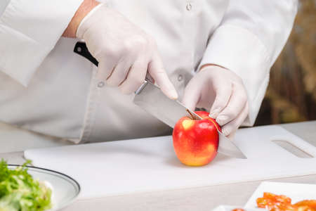 Male chef cutting an apple in half: selective focusの写真素材